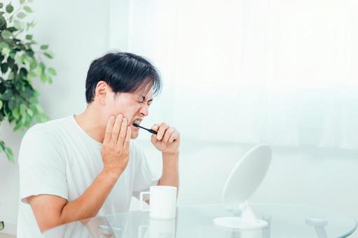 歯磨きで歯に痛みを感じる男性